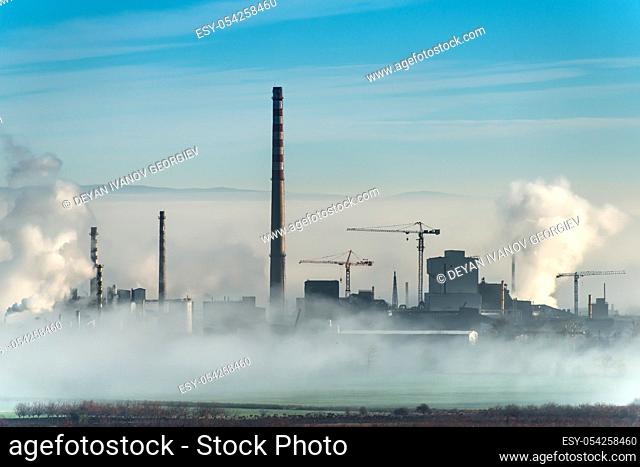 Factory chimneys and clouds of steam. Blue sky