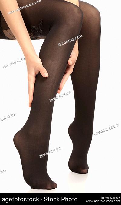 Close-up of female legs with pantyhose. Woman is rubbing her calf to relax pain