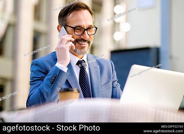 Senior businessman talking on smart phone sitting in cafe