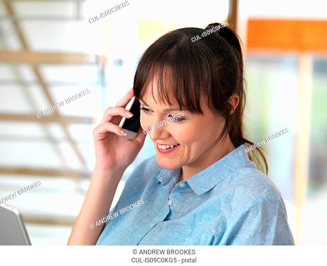 Woman smiling over the phone during a conversation at her desk