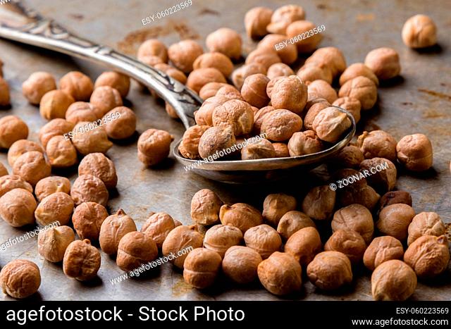 dry brown chickpeas on steel plate with spoon