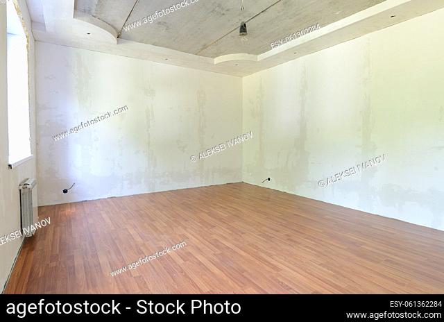 Interior of an empty room during renovation with plastered walls and laminate flooring