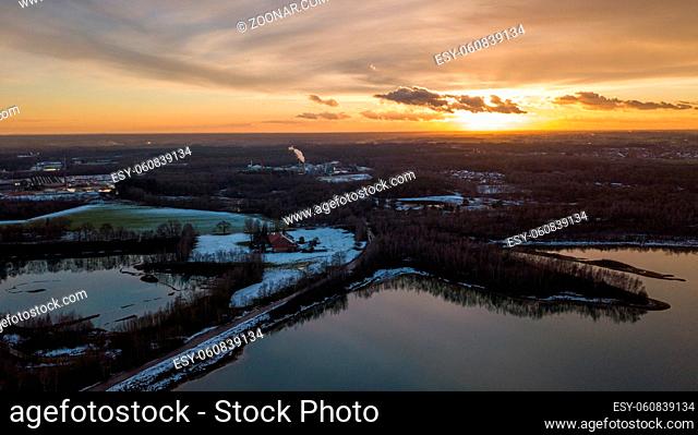 Aerial view of a beautiful and dramatic sunset over a forest lake reflected in the water, landscape drone shot. Blakheide, Beerse, Belgium