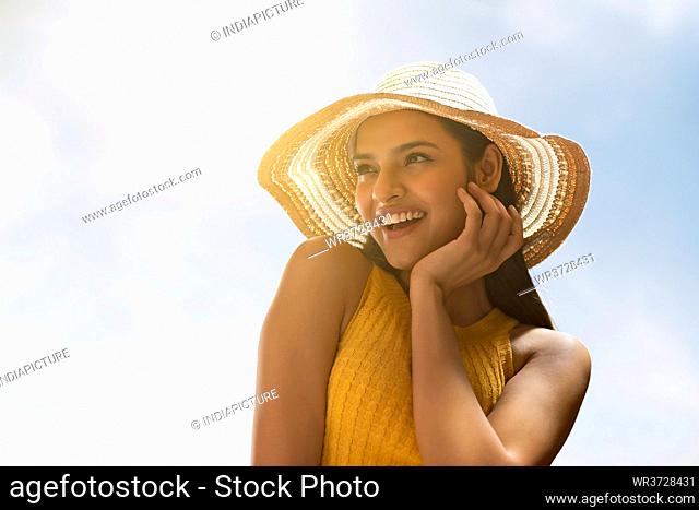 A HAPPY YOUNG WOMAN POSING ON A SUNNY DAY