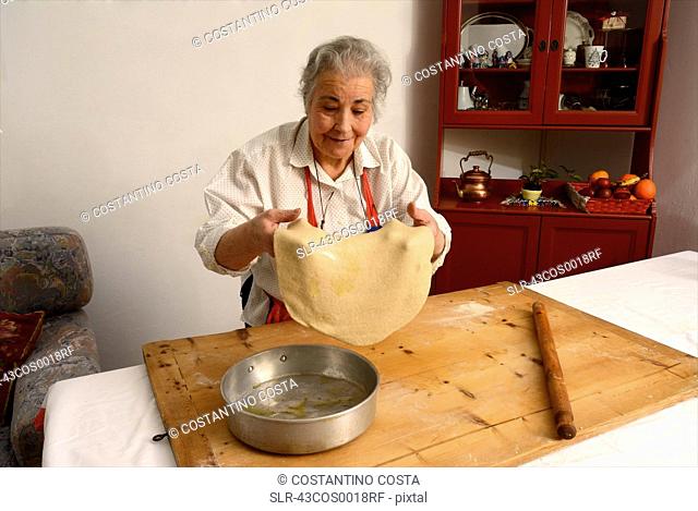 Older woman stretching sheet of dough