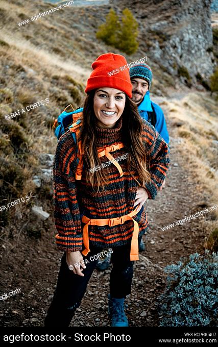 Smiling woman hiking with boyfriend on rocky mountain during vacation