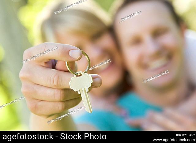 Happy couple holding blank house key outside with room for your own text on the key