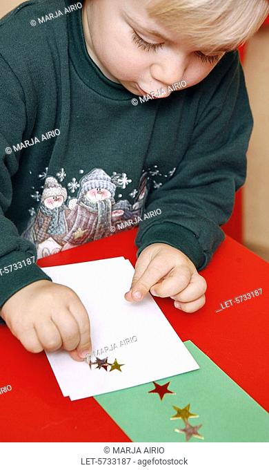 A two-year-old little boy is busy with star stickers