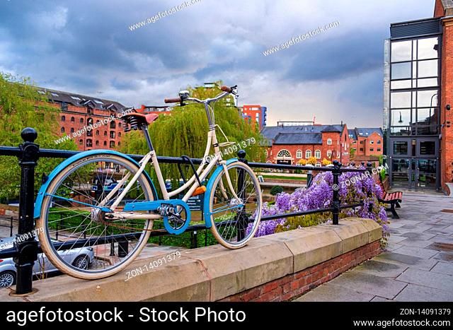 Manchester, United Kingdom - April 25, 2019: Atmospheric scene of a parked bicycle at the restored Victorian canal system in Castlefield area of Manchester