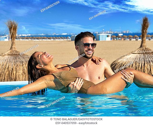 Tourist couple bath in infinity pool on a beach resort in summer vacation