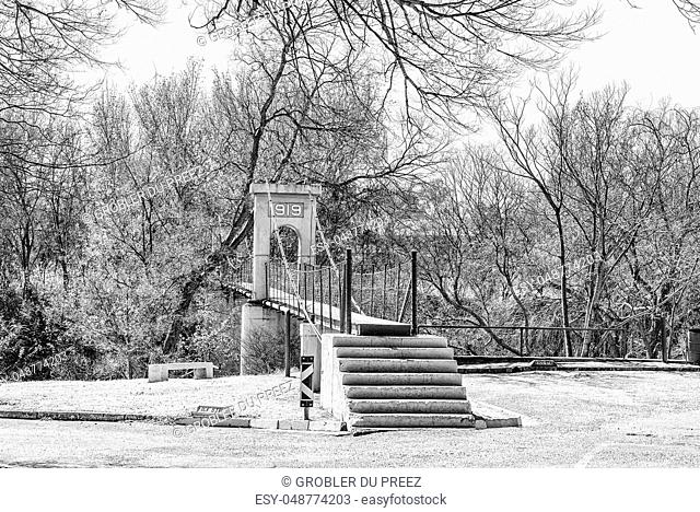 The historic suspension bridge over part of the Vaal River, built in 1919, in Parys in the Free State Province. Monochrome
