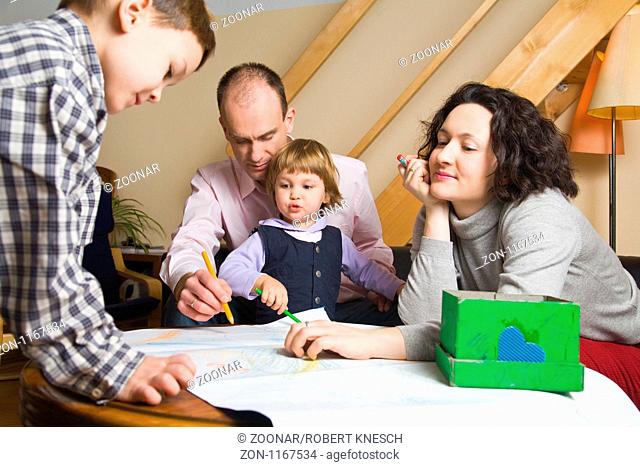 Familie mit zwei Kindern malt gemeinsam im Wohnzimmer
