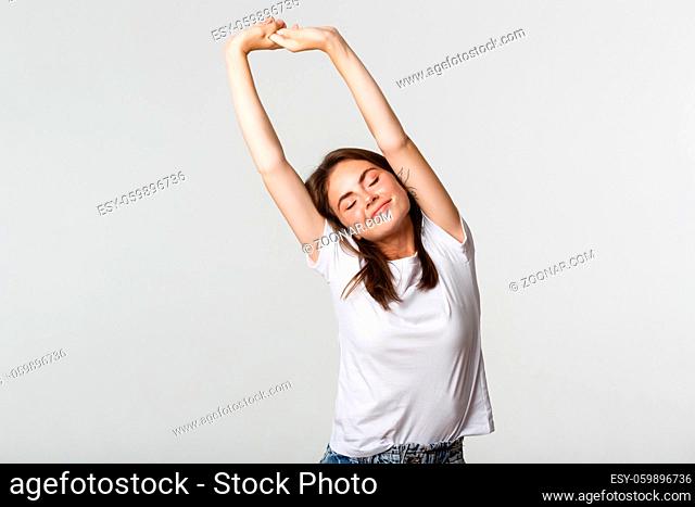 Portrait of relaxed carefree brunette girl stretching with satisfied smile