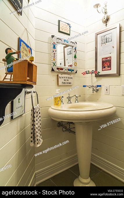 Vintage style pedestal sink and decorative folk art objects in powder room inside contemporary home, Quebec, Canada. This image is property released for...