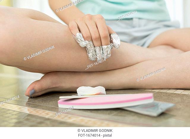 Low section of woman with covered finger sitting on floor