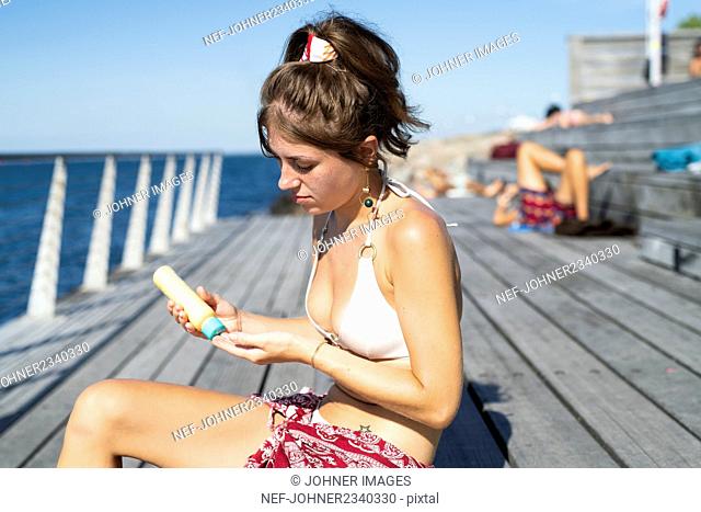 Young woman applying sun protector