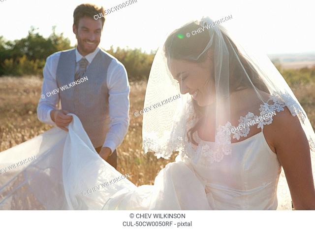 Newlywed groom holding brides dress