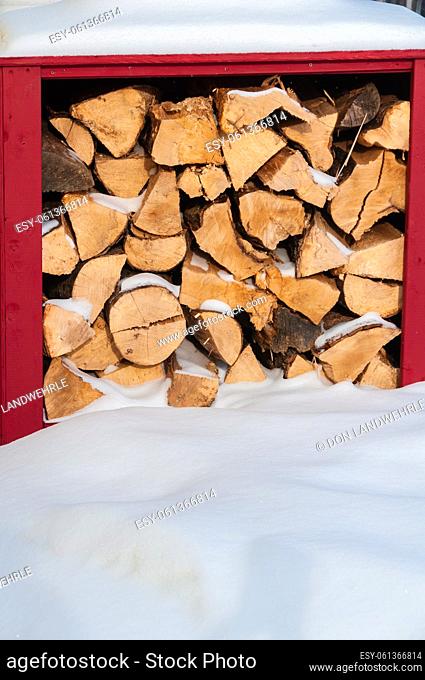 Firewood stacked in a red box covered with snow