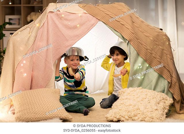 boy with pots playing in kids tent at home
