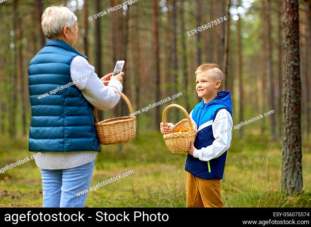 grandmother photographing grandson with mushrooms
