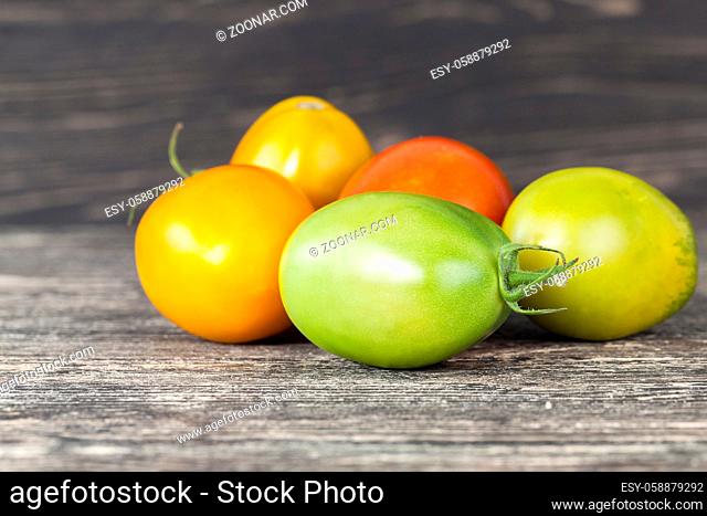 whole green red and yellow tomatoes on an old kitchen table
