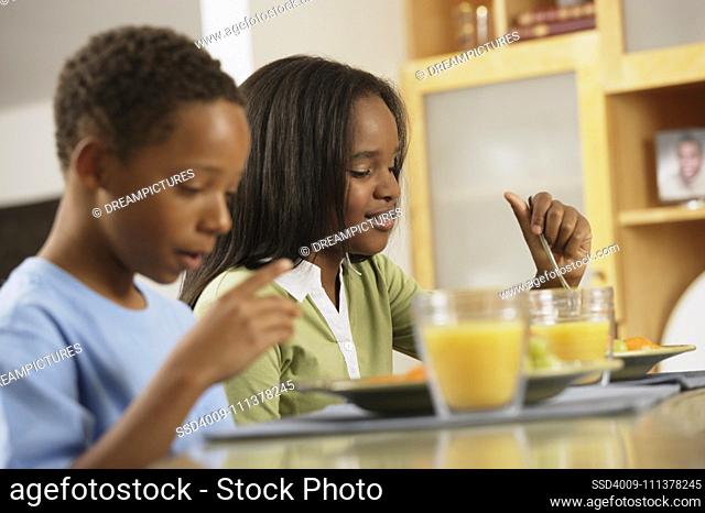 African brother and sister eating breakfast