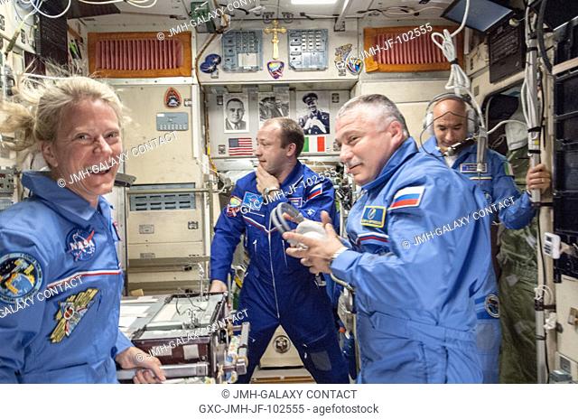 This image, photographed inside the Zvezda service module, is one of the first scenes showing interaction among the Expedition 36 crew members already onboard...