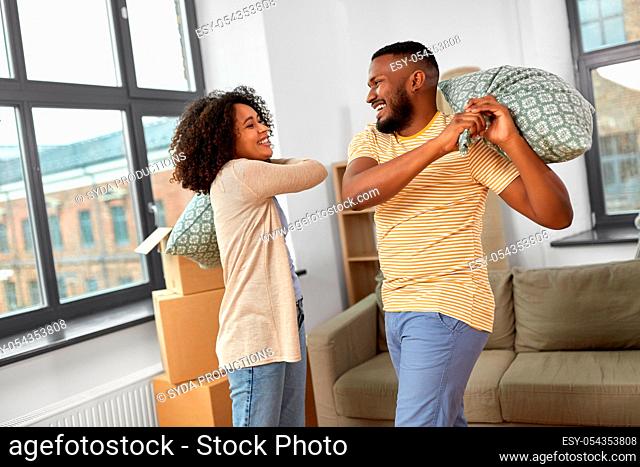 happy couple having pillow fight at new home