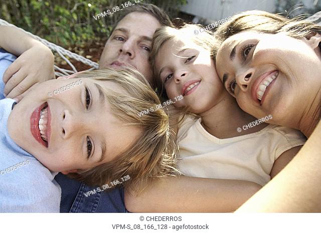 Close-up of a mid adult couple with their son and daughter lying in a hammock