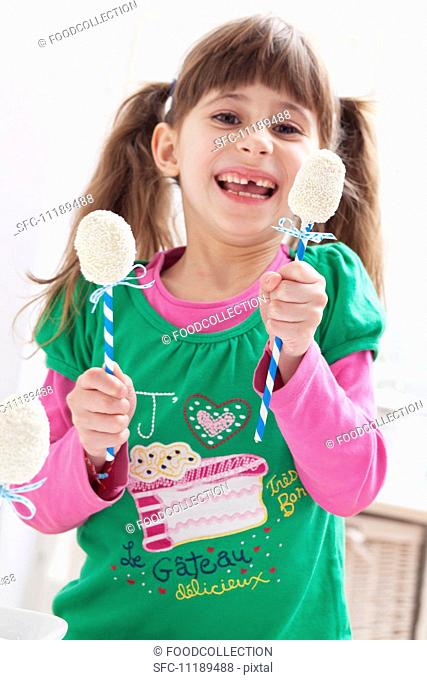 A girl holding two egg-shaped cake pops