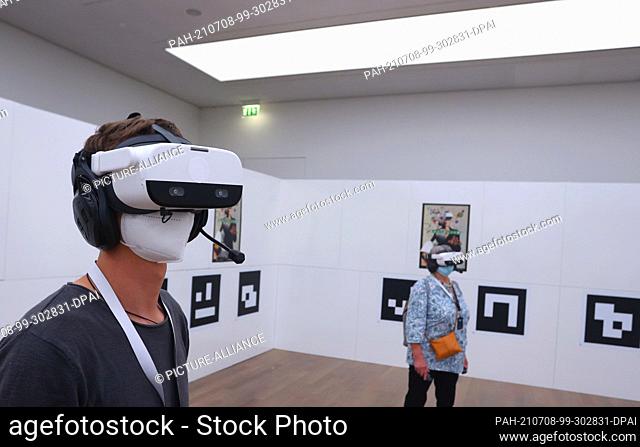 PRODUCTION - 06 July 2021, Baden-Wuerttemberg, Stuttgart: Visitors to the art museum stand with virtual reality glasses on in a room in which only QR codes hang...