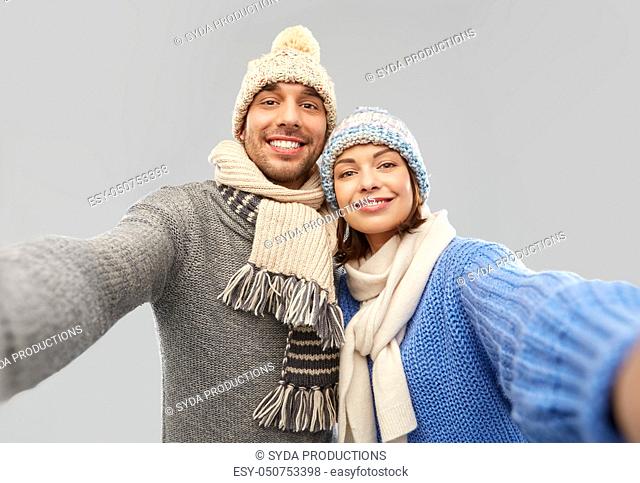 happy couple in winter clothes taking selfie