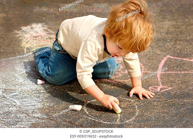Boy drawing outside with chalk