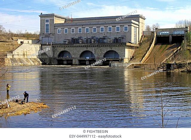 Narva, Estonia - May 1, 2017: people are fishing on the river Narva against the background of hydroelectric power station