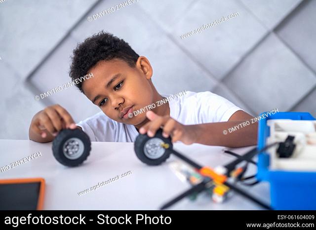 Toy wheels. A dark-skinned boy playing with toy vehicle wheels