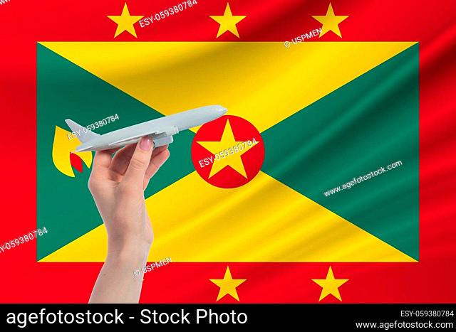 Airplane in hand with national flag of Grenada. Travel to Grenada