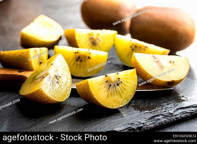 Halved ripe yellow kiwi fruit on cutting board