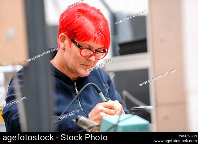 Industrial worker woman soldering cables of manufacturing equipment in a factory. High quality photo
