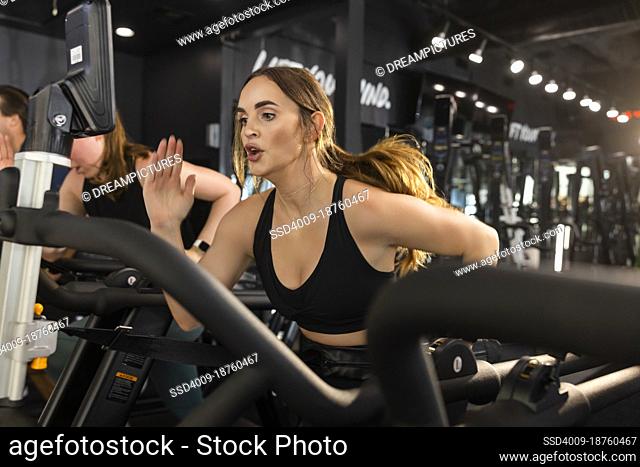 A determined woman training in a gym fitness center running on treadmill working hard