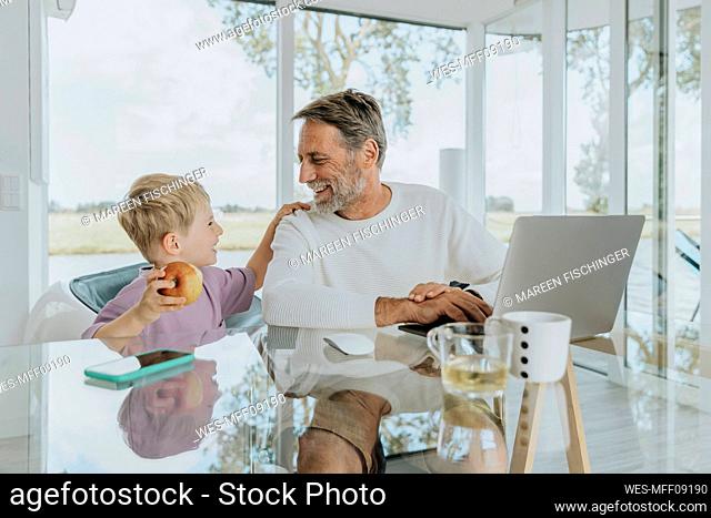 Happy mature man with son sitting at table