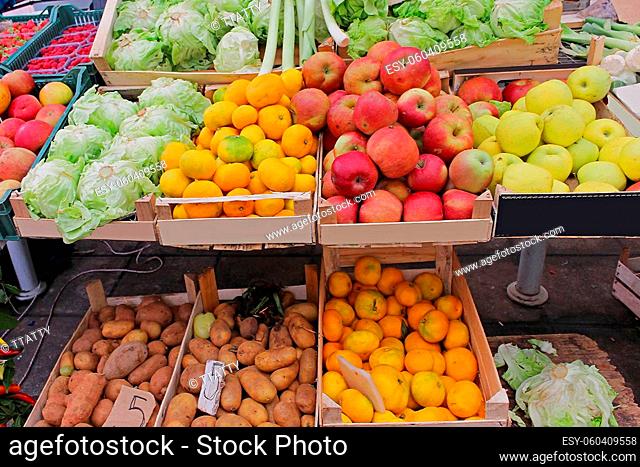 Organic fruits and vegetables in wooden crates sold on market stall
