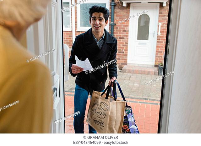 Teenage boy is delivering a bag of shopping to an elderly woman at home