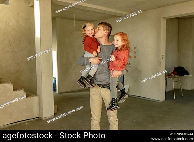 Father carrying cute daughters standing at home