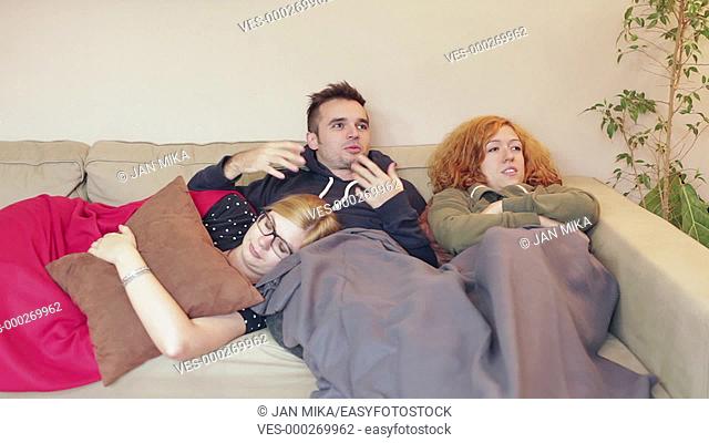 Group of happy friends resting together on the sofa at home