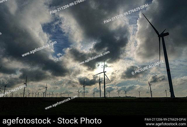 06 December 2021, Schleswig-Holstein, Ockholm: Wind turbines rotate in a wind field at Hauke-Haien-Koog on a dike of the North Sea coast