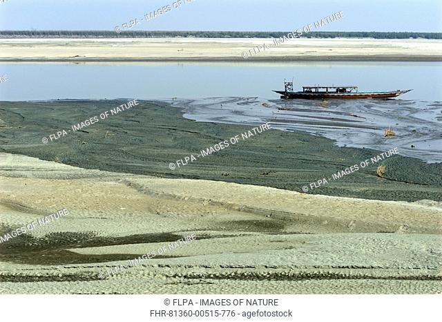 View of riverbank and river with low water levels, with stranded boat, River Brahmaputra, Kaziranga N.P., Assam, India, January