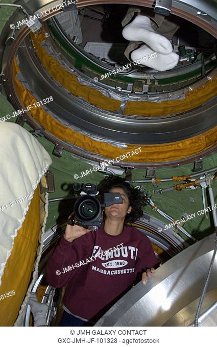 NASA astronaut Sunita Williams, Expedition 32 flight engineer, uses a High Definition Video (HDV) camera in the transfer compartment between the Zarya...