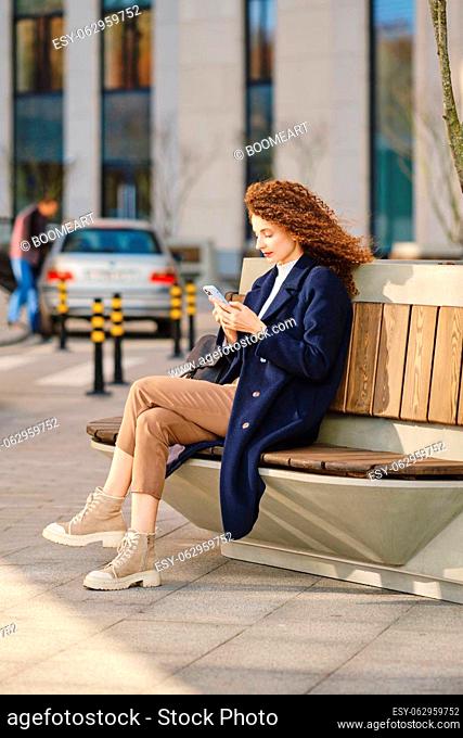 Woman orders a taxi using mobile application on her smartphone outdoors