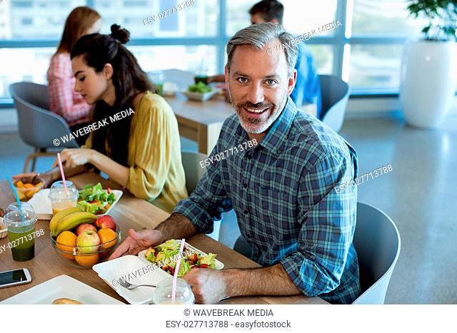 Smiling man having meal with his colleagues