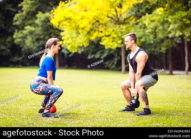 Fit and muscular couple focused on lifting a dumbbell during an exercise in the park